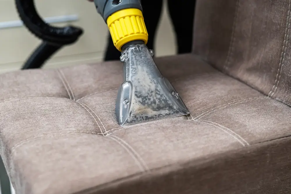 Woman cleaning a fabric chair with a professional washing vacuum cleaner